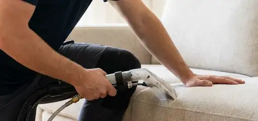 Professional upholstery cleaner deep-cleaning a fabric sofa with a handheld extraction tool, Riverside, CA.